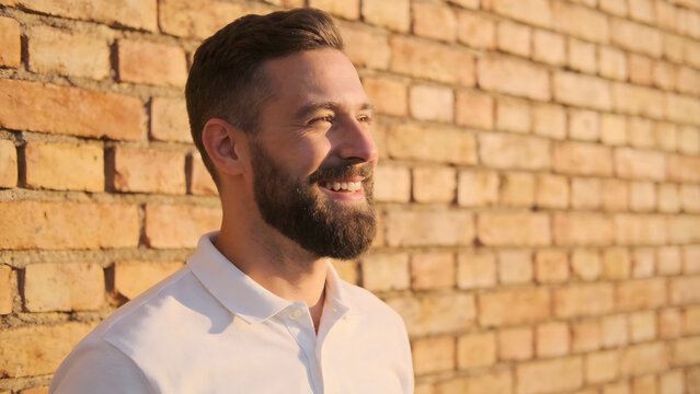 Man with beard smiling against brick wall