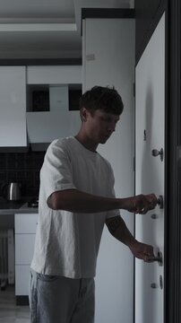 Psychological tension and hypervigilance concept with anxious man rushing into apartment, locking door and checking peephole for safety and protection, vertical video