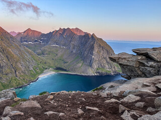 Obraz premium Dramatic mountain ridge overlooking a turquoise bay and ocean from a rocky cliff viewpoint