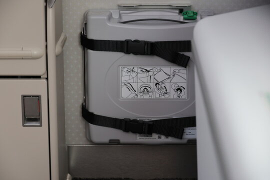 Protective breathing equipment box with instruction sticker inside an airplane cabin.