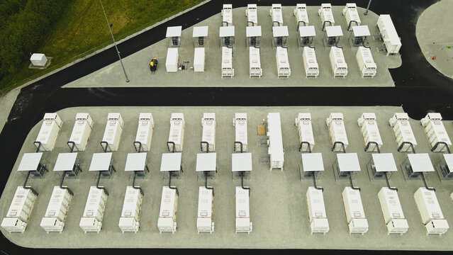 Aerial view showing large scale battery energy storage system with rows of white container units on a paved area, symbolizing energy independence and sustainable power infrastructure