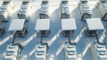 Fototapeta premium Aerial view showing multiple containerized battery energy storage units and associated infrastructure operating in a snow covered landscape, representing modern sustainable power solutions