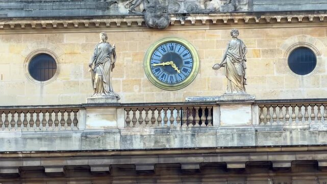 A detailed shot of the sculpted statues and architectural clock adorning the facade of the Palais de Justice in Paris, France