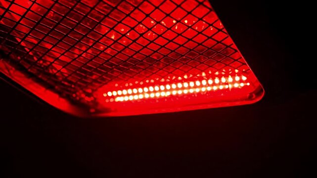Close-up of a glowing red infrared heater element with a mesh grill.