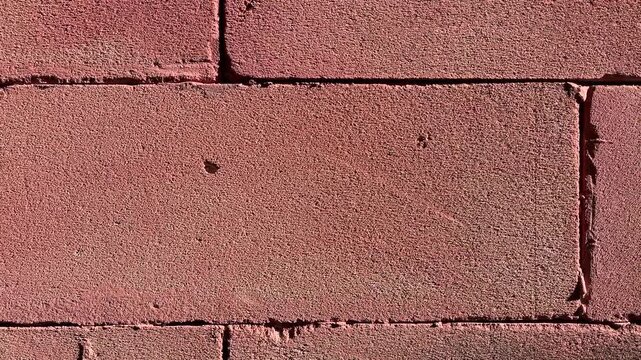 Red AAC lightweight brick wall texture in close-up with rough porous surface and construction material background under natural daylight.