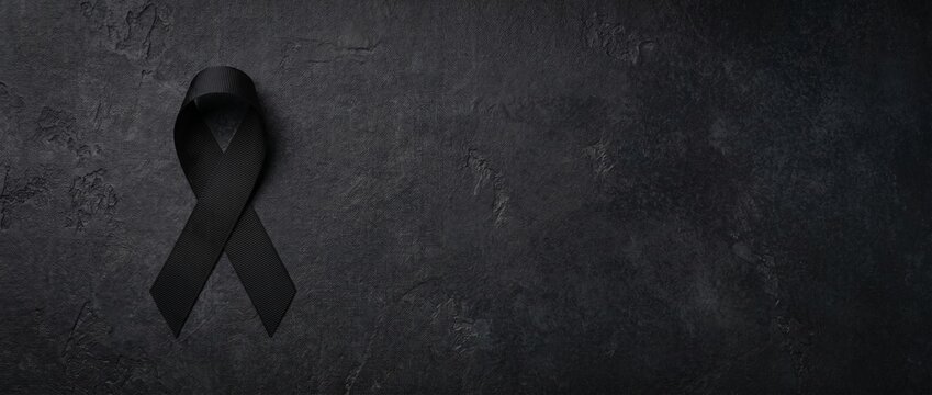 Black mourning ribbon on a dark textured background. Funeral service backdrop and memorial wallpaper, perfect for website banners with copy space