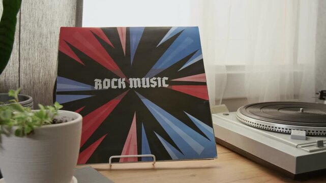 Close up detail shot of rock music vinyl record next to record player on coffee table in home interior, no people, copy space Great for retro music branding or vinyl store promo background