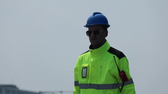 Electricians installing solar panels outdoors in the sweltering heat inspect solar panel installations rooftop wearing helmets and sunglasses they walk around conducting field inspections.