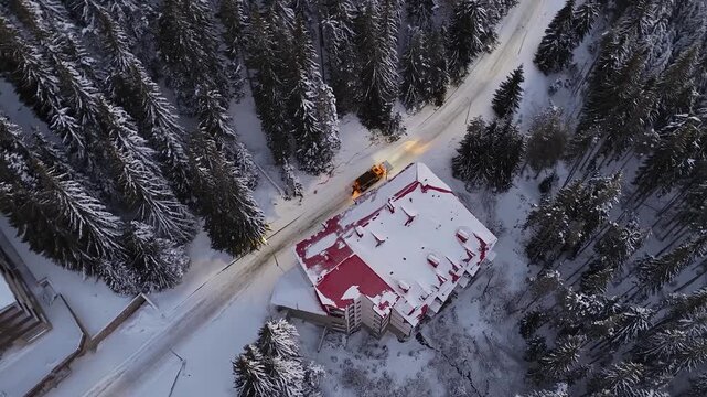 Professional Services snow plow truck maintaining safe road conditions under streetlights during nighttime and clear mountain ski resort snow covered roads after heavy winter storm snowfall