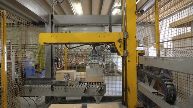 Industrial robot arm stacking coolant boxes on pallet in automated factory area