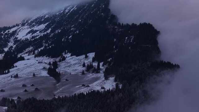 Snowy mountain landscape partially obscured by dense clouds fog Amden Switzerland