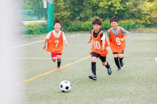 ドリブルの後シュートでゴールを狙うサッカー少年たち