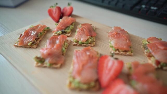 Snack items are arranged neatly on a wooden board, featuring thin slices of salmon on crisp bases topped with greens
