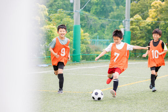 ドリブルの後シュートでゴールを狙うサッカー少年たち