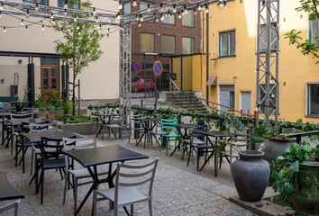 Fototapeta premium Cozy outdoor cafe courtyard with string lights and modern seating in urban residential district during summer evening