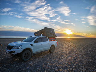 Overlanding 4x4 truck with rooftop tent on the beach at sunset. © SobrevolandPatagonia