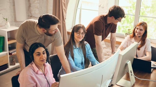Office support team reviewing customer service tasks near computers. Concept of call center coordination, helpdesk workflow, staff training, client care, and service management.