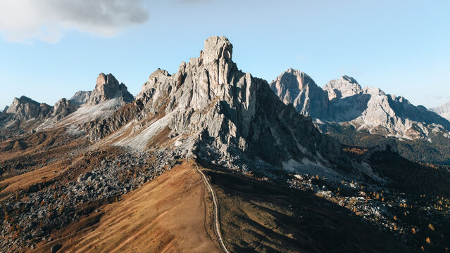 Aerial view of Passo Giau mountain pass and the Ra Gusela peak with rugged rocky slopes and a narrow winding trail in Colle Santa Lucia, Veneto, Italy.