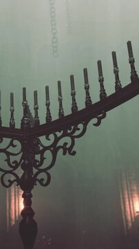 A menora stands tall in a dimly lit room. The candles are unlit and the metal design is visible. The atmosphere has a mysterious feel, with shadows cast on the walls.