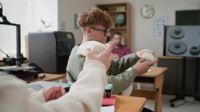 Over the shoulder shot of students examining 3D-printed car models at their desks after hands-on modeling class at school