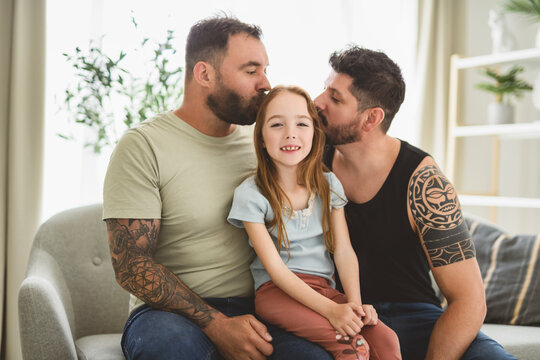 homosexuals gay couple love each with his lovely adopt little girl on sofa