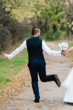 bride and groom walking along a path in an autumn forest