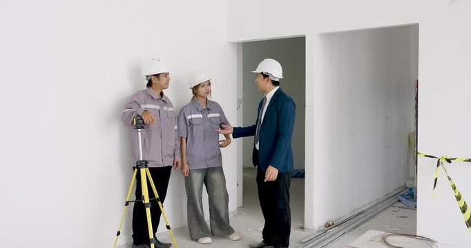 Asian female engineer, worker, and business manager coordinate building site progress near survey equipment, discussing construction quality control, safety planning, contractor instruction.