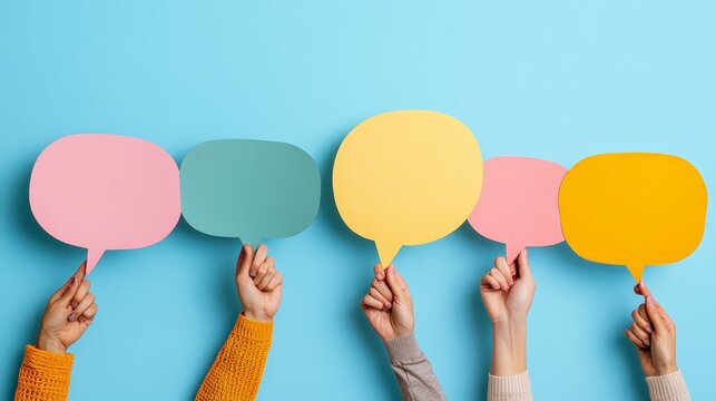 Hands holding vibrant, empty speech bubbles against a blue background, representing open communication and embracing diverse perspectives in conversation and discussion