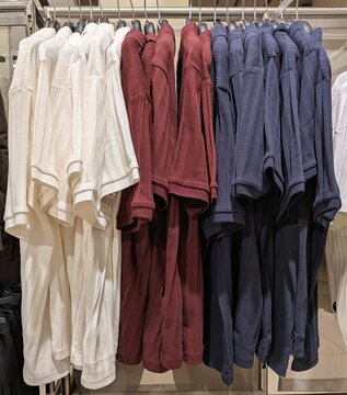 Camisa polo de manga corta de hombre, ordenadas por colores, colgadas en un expositor de una boutique de ropa