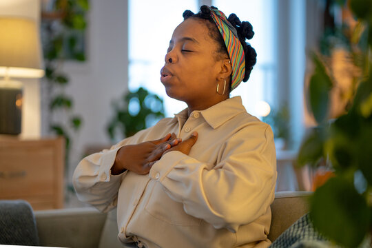 Mindful break of black woman using conscious breathing technique to calm anxiety and restore emotional balance at home. Self regulation, coping with stress, mindfulness, mental health, wellness habits