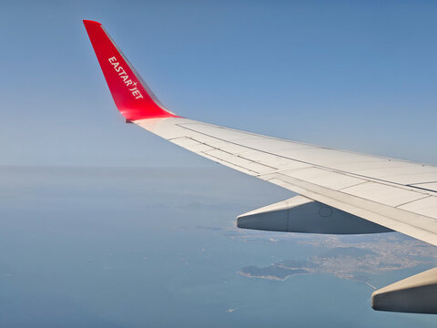 April 25, 2026: An aerial view from the window showing the wing and red winglet of an Eastar Jet Boeing 737 passenger airplane flying over the blue ocean.