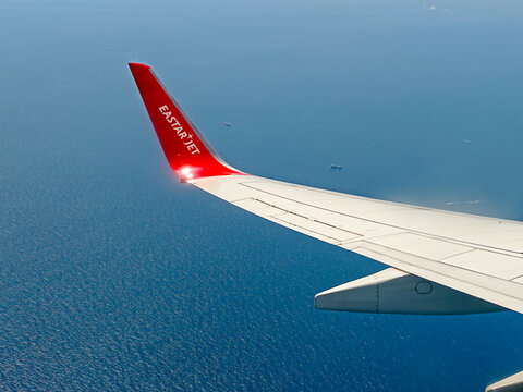 April 25, 2026: An aerial view from the window showing the wing and red winglet of an Eastar Jet Boeing 737 passenger airplane flying over the blue ocean.