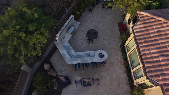 An aerial view of a desert landscaped backyard in Arizona featuring a travertine tiled pool deck outdoor fireplace and kitchen.