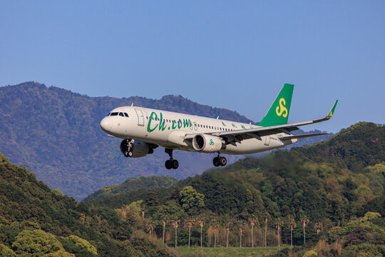 Fukuoka, Japan - May 26, 2026: A Spring Airlines Airbus A320 (Registration B-1839) on final landing approach to Fukuoka Airport, with lush green mountains in the background.