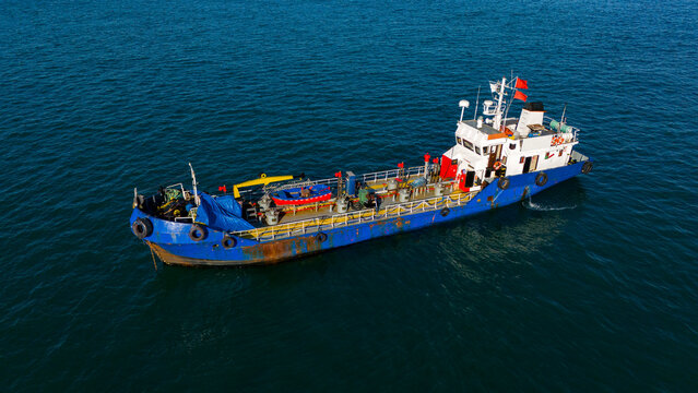 Drone side view of blue offshore support boat floating on open water