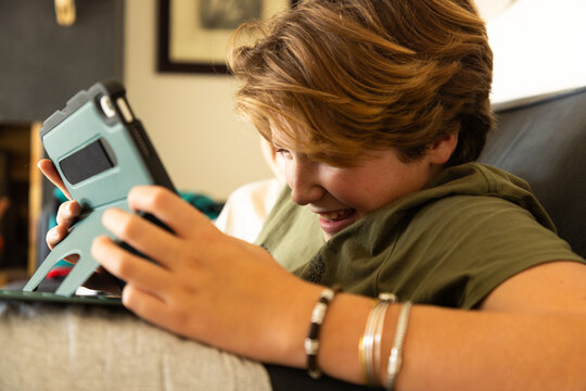 12 year old boy using tablet computer for gaming