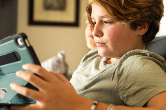 12 year old boy using tablet computer for gaming