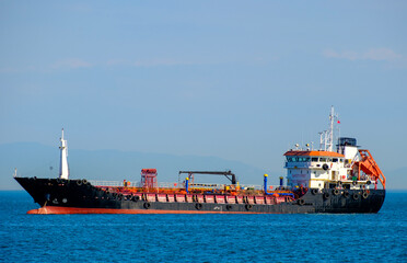 Fototapeta premium Lengthy black and red oil product tanker sailing on a clear day