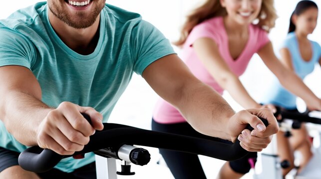 Man and women cycling on spin bikes in fitness studio