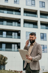 Entrepreneur talking on smartphone and reviewing blueprints