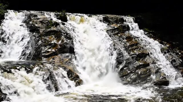 A multi-layer waterfall alpha channel loop with several streams flowing at different speeds over rocky surfaces, isolated on black background with endless natural water motion.