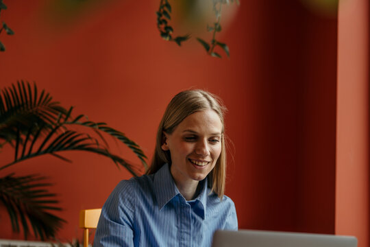 Smiling woman using laptop for casual home office work