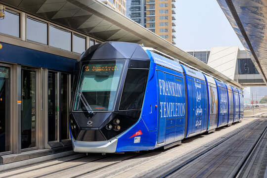 Dubai, UAE - August 16, 2025: An Alstom Citadis LRT vehicle wrapped in a Franklin Templeton advertisement stopped at a station platform with synchronized platform screen doors on the Dubai Tram networ