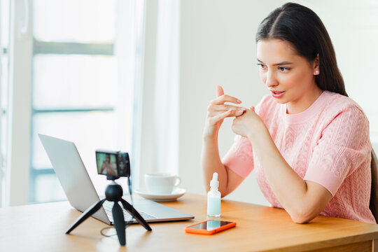 Young woman working with laptop computer in home kitchen. Work at home. Freelance, remote work. Woman advertises cosmetic products online