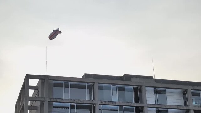 Large airship floats over modern city streets capturing attention of people below in urban setting