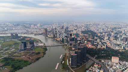Fototapeta premium Drone aerial panoramic view of the Saigon River, Ba Son Bridge, and the modern city skyline of District 1 in Ho Chi Minh City, Vietnam.