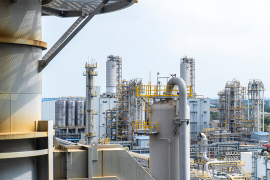 Industrial background of a large-scale chemical factory and oil refinery with complex pipelines, distillation towers, and storage tanks under a clear sky.