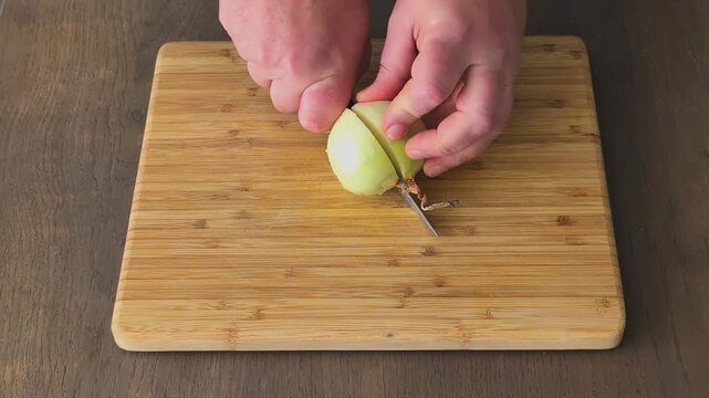 Chopping onions at a kitchen counter using a knife and cutting board in a simple cooking task