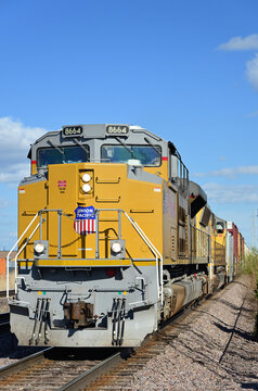 A westbound Union Pacific Railroad merchandise freight train, led by multiple locomotives, slowly moves through a Chicago suburb.