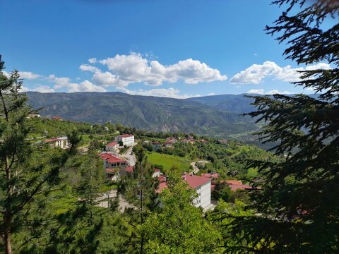 Scenic landscape view of a small mountain village in Koyulhisar, Sivas, Turkey with red-roofed houses in a lush green valley.